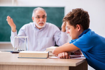 Old male teacher and schoolboy in the classroom