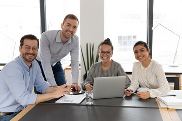 Business team of happy diverse employees looking at camera at workplace. Group of mixed race managers posing for corporate portrait during meeting and discussion of work success. Teamwork concept