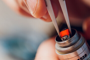 Specialist replaces spring for smoking vape.Professional maintaining electronic cigarette in...