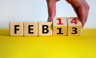 February 14 valentines day symbol. Hand turns cubes and changes the word 'Feb 13' to 'Feb 14'. Beautiful yellow table, white background, copy space. February 14 Valentines day concept.