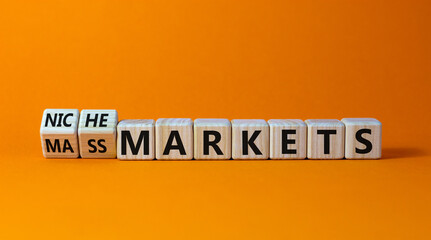 Mass or niche markets symbol. Turned wooden cubes and changed words 'mass markets' to 'niche markets'. Beautiful orange background, copy space. Business and mass or niche markets concept.