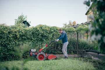 A man works in the garden, plows the soil with a cultivator