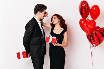Shapely girl in black dress celebrating anniversary with husband. Studio shot of couple exchanging...