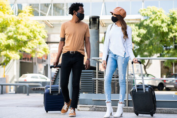 Fototapeta na wymiar Tourist couple carrying suitcase while walking outdoors.