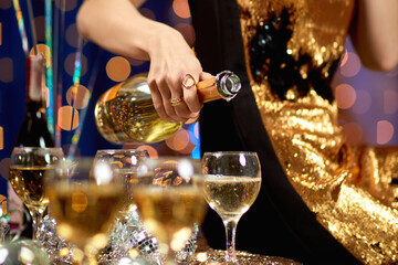 close-up of female hand with is pouring champagne into a glass. party and holiday celebration