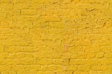brick wall with an uneven surface painted with yellow paint, fragment, seamless texture