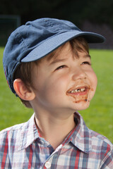 Junge mit Schokoladenmund lacht in die Sonne