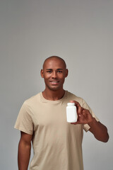 Man presenting a white medicine bottle with a smile