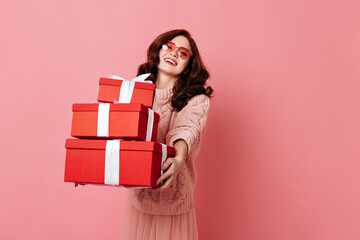 Gorgeous young woman holding valentine gift. Studio shot of curly ginger girl celebrating birthday.