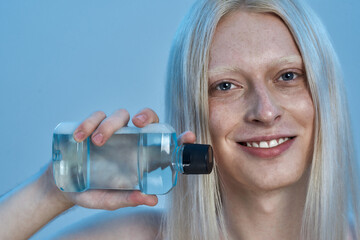 Happy young caucasian man holding mouthwash liquid