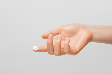 A drop of thick white hand cream on the finger of a woman's hand. Groomed hands, natural short...