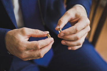 The groom holds the gold wedding rings with his fingers 2560.