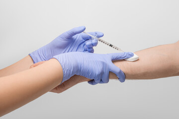 A doctor wearing latex gloves gives the vaccination to the patient. 1 ml disposable syringe,...