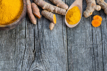 Turmeric powder in spoon or bowl and fresh turmeric root on wooden background, spice concept, ( curcuma longa ) - obrazy, fototapety, plakaty