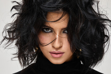 portrait of gorgeous beautiful curly brunette woman is looking at the camera on studio background