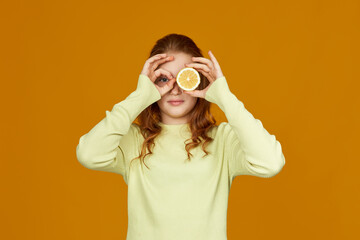 Fototapeta premium little child girl holding fresh juicy lemon isolated on yellow background