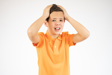 Handsome teen boy covers his head and ears with his hands, isolated on red background