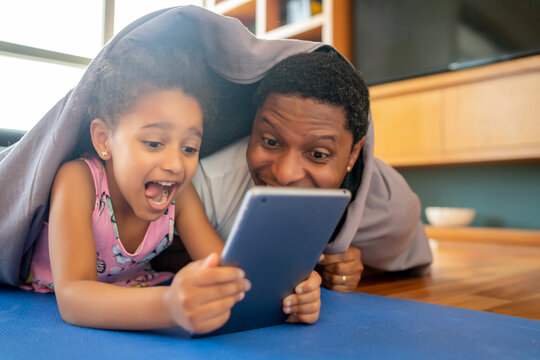Father and daughter using digital tablet at home.