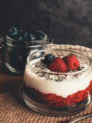 CREAMY YOGURT WITH RASPBERRIES AND BLUEBERRIES ON A DARK BACKGROUND