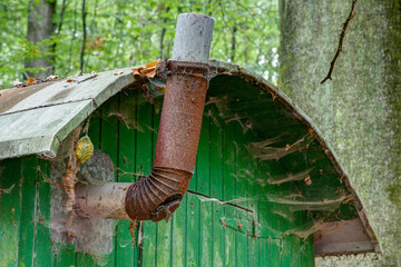 Old rusted metal stovepipe and cobwebs under the tin roof on a weather protection caravan for...