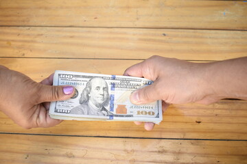 Two hands holding dollar bills