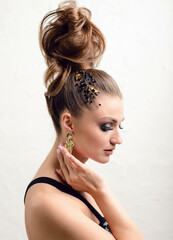 Woman with evening makeup and high hair bun. Beauty portrait with jewelry in hair