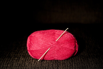 Woolly knit threads fuchsia with a hook on a dark background.