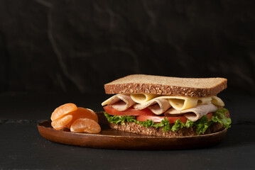 Healthy sandwich on black background, served with fruit