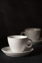 Two empty espresso cups viewed from the side against black background 