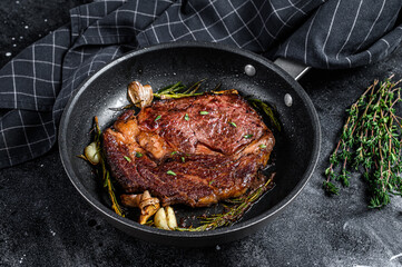 Roasted rib eye steak, ribeye beef meat in a pan. Black background. Top view