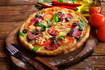 Pizza with mushrooms, sausage and olives on a wooden background