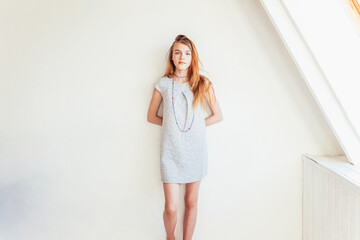 Happy teenage girl smiling. Portrait young happy positive teen woman in grey dress at home in...