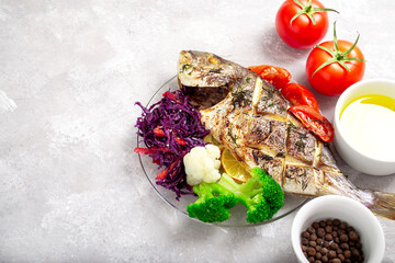 Oven-cooked dorado fish with colored vegetables and cabbage salad.