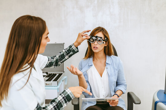 Female optometrist checking patient's vision at eye clinic. Healthcare and medical concept.