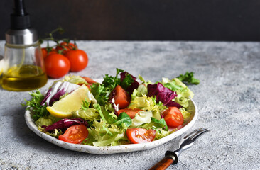 Vegetable mix salad with tomatoes and sauce on a concrete background.