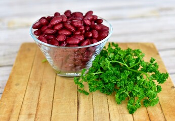 Red Kidney beans in glass bowl with fresh herbs ready for preparing healthy vegan or vegetarian meals. Simple bowl of beans photo concept with copy space