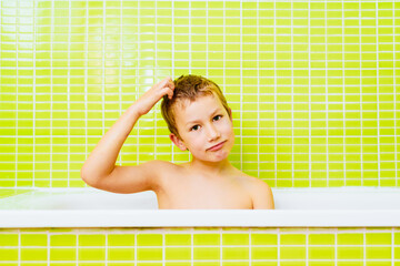 Boy with head lice in a bathtub frantically scratches his head because it itches.