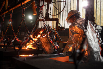 Steel casting process. Worker in foundry filling molds with molten iron.