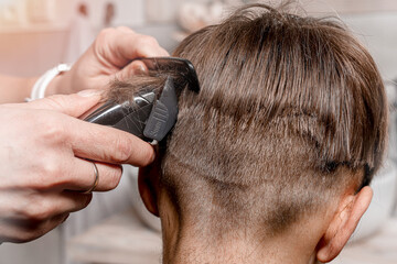 Detail on the shaver and comb. Mom cuts her son in the bathroom.