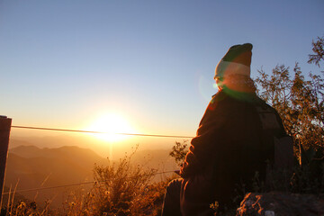 Viajero viendo el amanecer desde la cima de una montaña