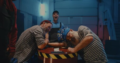 Men arm wrestling for money in garage