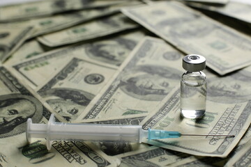Vaccine vial and syringe on the background of one hundred dollar bills