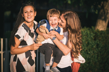 Mom and aunt holding cute, little boy. Family love