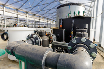 Fototapeta na wymiar Large industrial water treatment and boiler system in a greenhouse with many pipes and valves