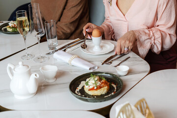 Obraz na płótnie Canvas A woman peels an egg for breakfast in a restaurant. Selective Focus