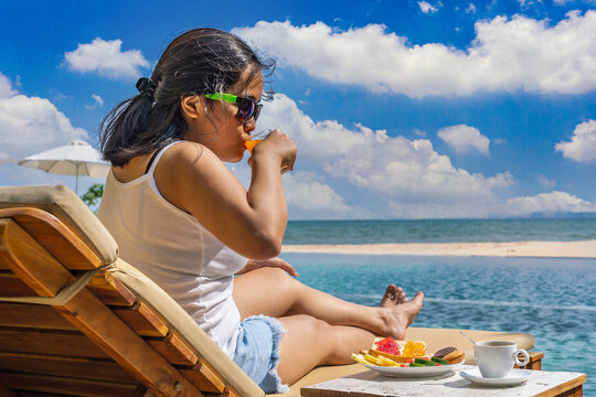 Asian woman relax and drink orange juice in the beach