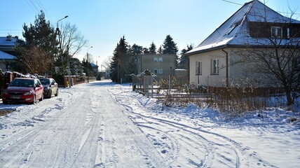 Residential neighborhood in the suburbs during a white snow storm and roads covered in snow. 