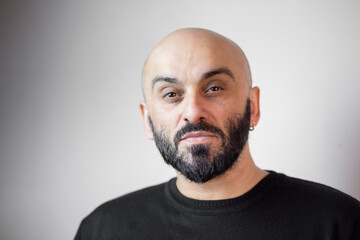 Close-up portrait of bearded bald man. White background