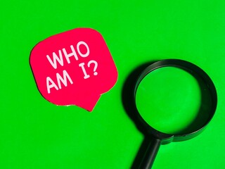 Q and A concept.Top view red bubble speech written WHO AM I with magnifying glass isolated on green background.