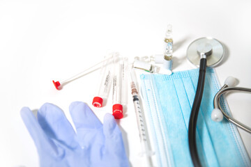 medical supplies, glasses, gloves, surgical mask, syringes and ampoules on a white table